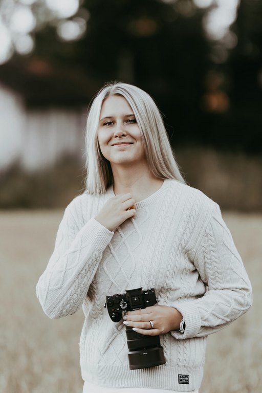 Valokuvaaja Jonna Helinin omakuva ulkona vaalean sumennetun taustan edessä